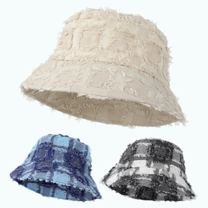 Detailed view of frayed edge bucket hats in beige, blue plaid, and black white patterns