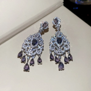Detail of luxury teardrop purple zircon fringe earrings with silver plating and micro-pave crystals