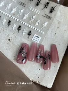 Dettaglio di adesivi 3D a rilievo per unghie con rose bianche e nere per manicure