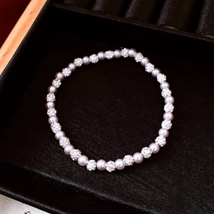 Close-up of pink pearl bracelet with pavé crystal balls on black velvet tray