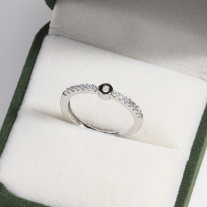 Detail of silver paved ring with black circular motif in green velvet jewelry box