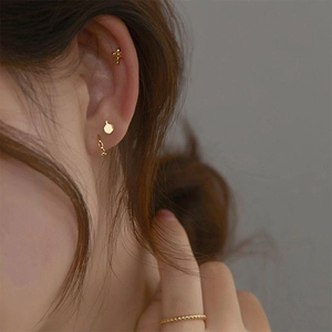 Detailed view of matte gold earring set and minimalist band ring worn by a model