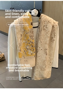 Detail view of yellow and beige floral cotton linen scarf draped on a white knit top