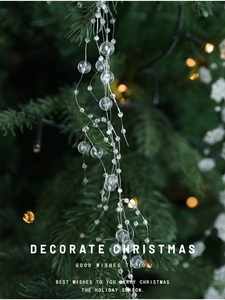 Close-up of transparent Christmas bead garland hanging on a green pine tree branch