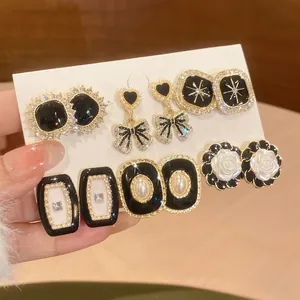 Vintage gold-tone pearl and enamel earring set with rhinestone accents on a card