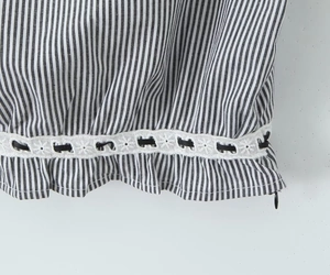 Detailaufnahme von gestreiftem Stoff mit weißer Spitze und schwarzem Kordelzugband