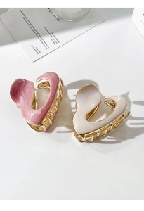 Close-up of pink marble and white heart-shaped hair claw clips with gold metal teeth