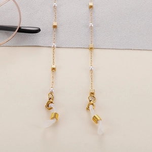Detail of golden mask chain with square beads, pearls and white silicone connectors