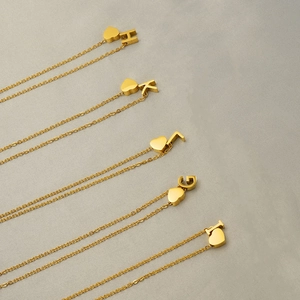 Detailed close-up of gold stainless steel heart and alphabet letter pendant necklace
