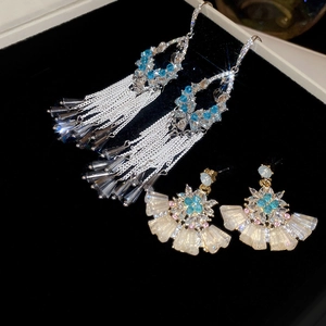 Detailed macro of crystal fan earrings with silver tassels and blue rhinestones