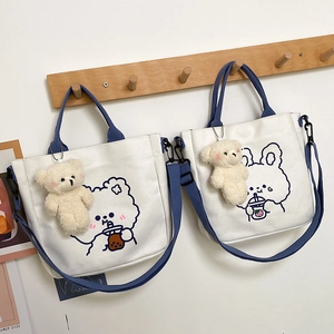 Detail of canvas tote bags with cute cartoon bear and rabbit prints on wall hooks