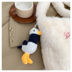 Detail of seagull plush pendant in corduroy fabric attached to a white fuzzy bag