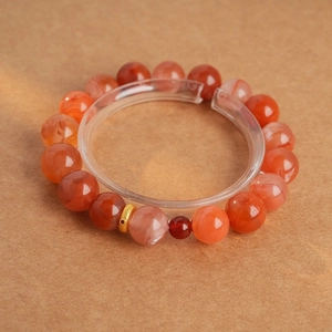 Close-up of red agate beaded bracelet with a single textured gold metal bead accent