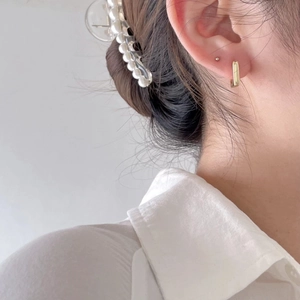 Minimalist gold square hoop earrings worn by a model with a pearl hair clip background