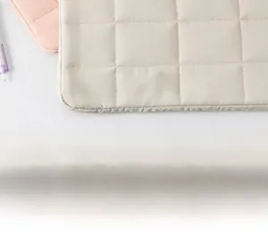 Close-up of beige quilted textile laptop sleeve with square stitching pattern detail
