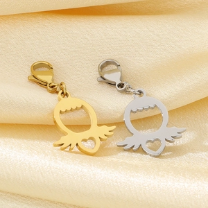 Détail de pendentifs ailes en forme de cœur dorés et argentés sur tissu satiné jaune