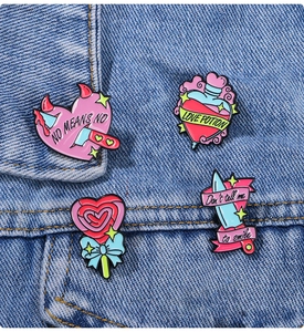 Close-up of assorted pink enamel pins with slogans on blue denim jacket fabric