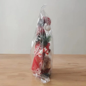 Detailed view of a Christmas gnome doll with red plaid hat and candy cane in plastic bag