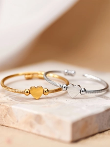 Detail of gold and silver heart cable bangles on marble stone texture background