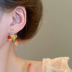 Macro shot of colorful resin tassel earrings worn by a model in warm soft lighting
