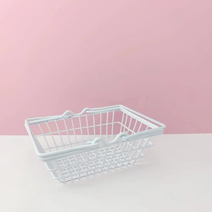 Close-up of a white metal mesh storage basket with dual handles for desktop organization