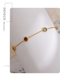 Detail showing gold chain bracelet with colorful round crystals on a white stand