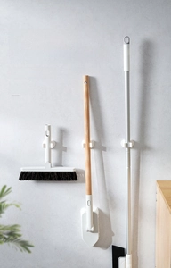 Close-up of wall-mounted mop holder with C-shaped elastic clips for broom storage