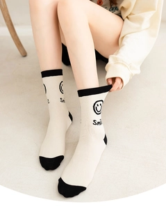 Detail shot of beige cotton crew socks with black smile icon and ribbed cuff