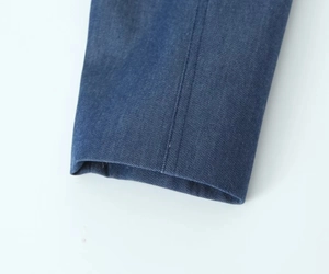 Macro view of dark blue denim sleeve cuff with reinforced double-needle stitching detail