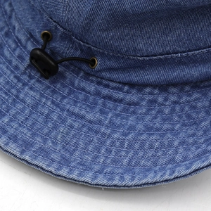 Détail du chapeau bob en denim bleu avec cordon de serrage et œillets d'aération en laiton