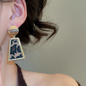 Close-up of vintage leopard print trapezoid drop earrings with gold metal frames