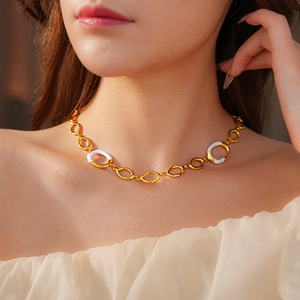 Close-up of golden necklace with white enamel oval links worn on a model's neck