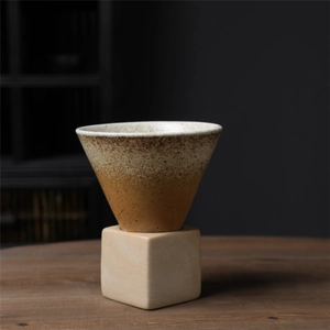 Detailed close-up of a rustic ceramic pour-over coffee dripper set on a dark wooden table