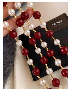 Dettaglio macro di perle rosse e bianche con accenti dorati su una collana di lusso