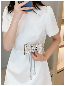 Close-up of a silver bow-shaped metallic evening bag with a polished mirror finish and chain