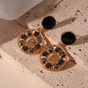 Détail macro de boucles d'oreilles vintage en or avec clous noirs et cristaux gris sur pierre
