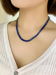 Close-up of a necklace featuring blue rectangular gemstones on a female model