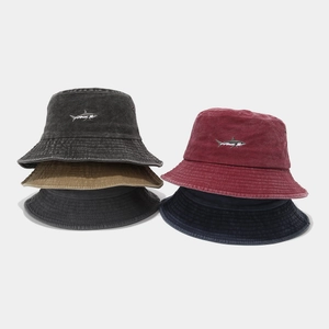 Detailed pile of washed cotton bucket hats featuring shark embroidery in various colors
