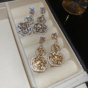 Detail view of gold and silver hollow gourd earrings with zircon floral patterns