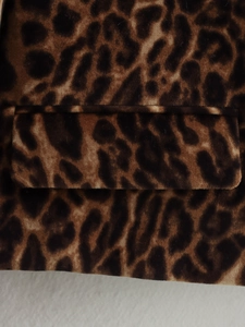 Detailed close-up of leopard print fabric texture and pocket design on a blazer