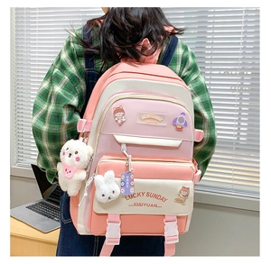 Pink and white school backpack detail with plush bear pendant and cute cartoon badges