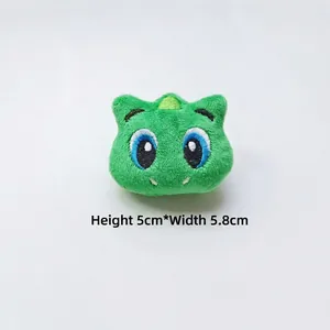Detailed view of green plush dinosaur charm with embroidery, size H 5cm x W 5.8cm