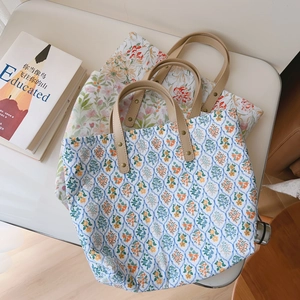 Gros plan sur les sacs cabas en coton fleuri avec poignées en cuir et rivets en métal