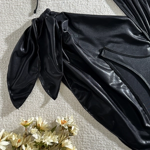 Détail de la matière noire brillante avec nœud décoratif et lacets sur le maillot