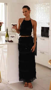 Close-up of sleeveless black chiffon set featuring tiered pleated maxi skirt and halter top