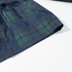 Gros plan du tissu rétro à carreaux bleu-vert avec cordon à la taille et coutures détaillées