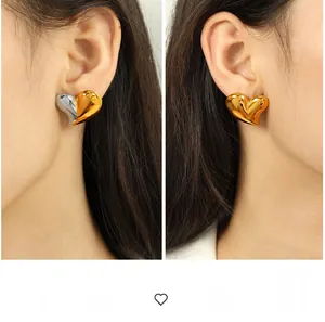Gros plan sur des boucles d'oreilles cœur exagérées en finitions or et argent poli