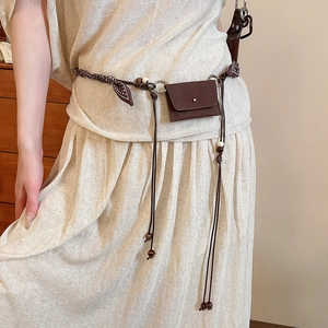 Detail of bohemian brown woven belt featuring a small pouch and wooden bead tassels