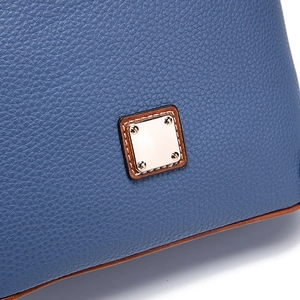 Close-up of textured navy blue pebble leather with metallic plaque and brown trim detail