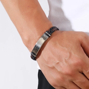 Close-up of woven black and brown leather bracelet with polished silver metal plaque